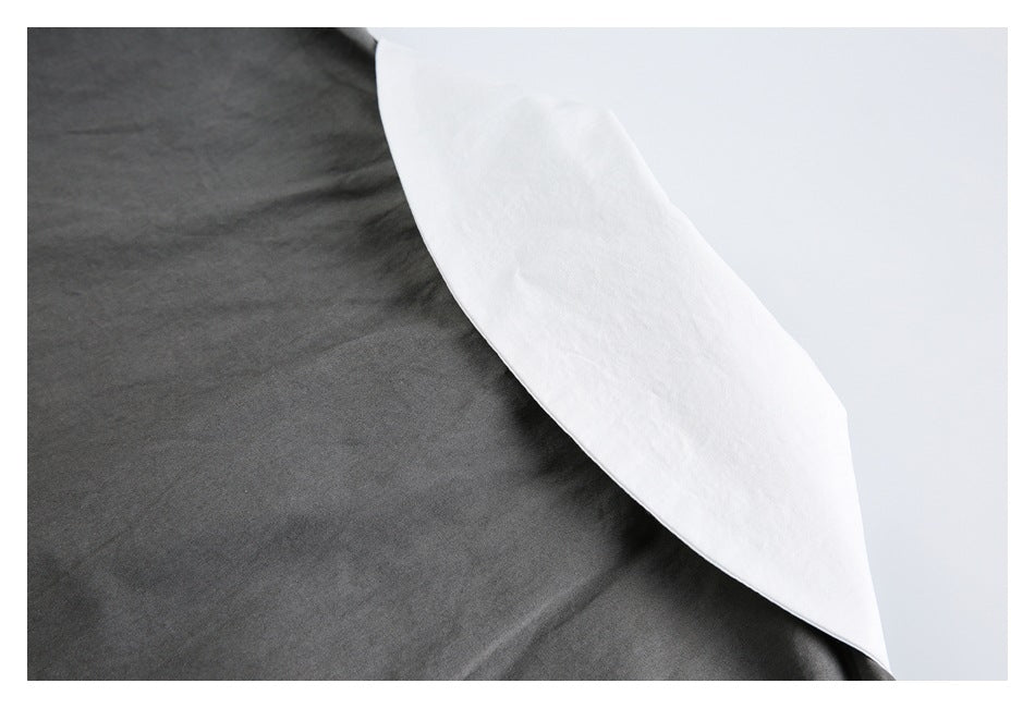 Close-up of charcoal gray garment fabric beside a curved white inner layer.