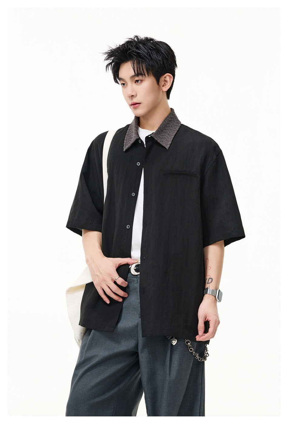 Model wearing a black short-sleeve button-up shirt with a textured gray collar and chest pocket, over a white tee.