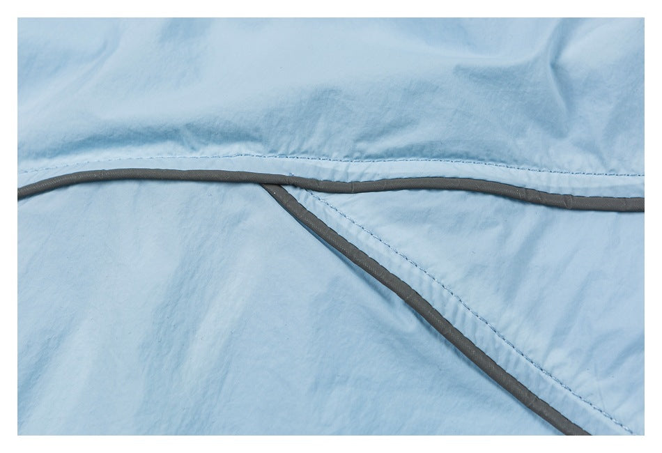 Close-up of pale blue fabric with curved stitched seams and dark gray piping.