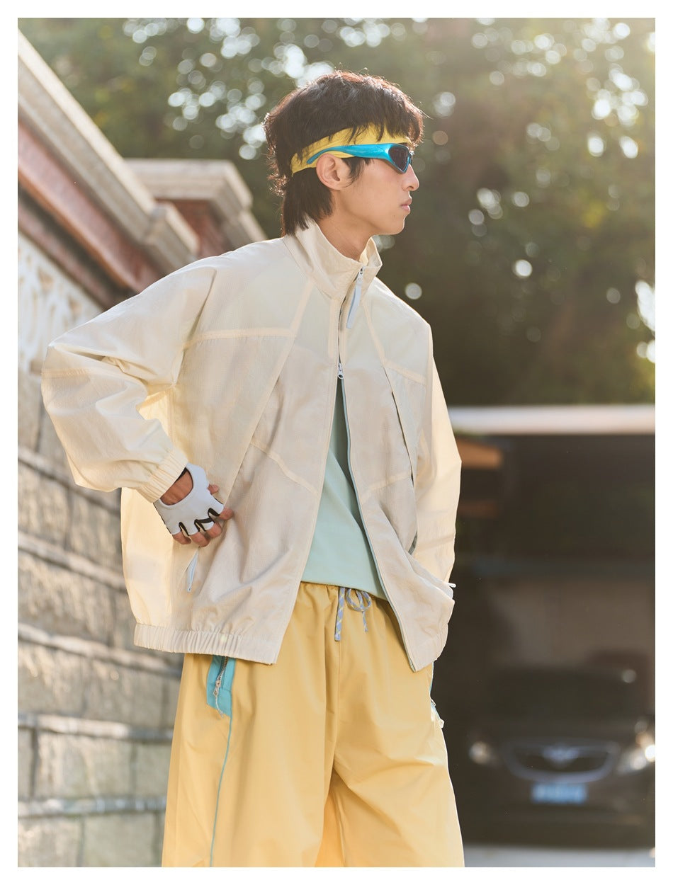 Model wearing a cream high-collar zip jacket with panel details, paired with mustard trousers.