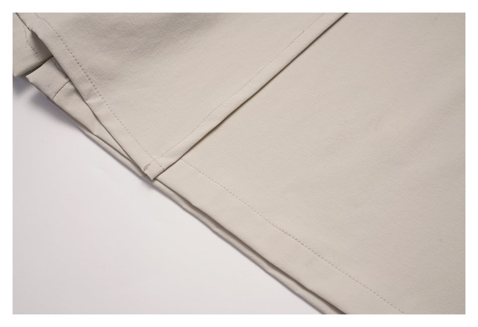 Close-up of a folded seam and stitching on light beige garment fabric.