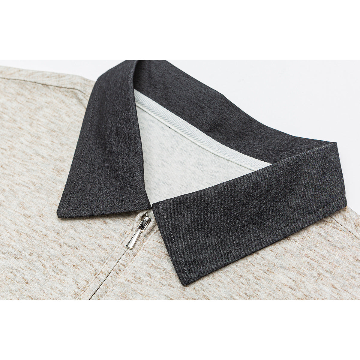 Close-up of a light heather beige shirt with a dark charcoal collar and short zipper.