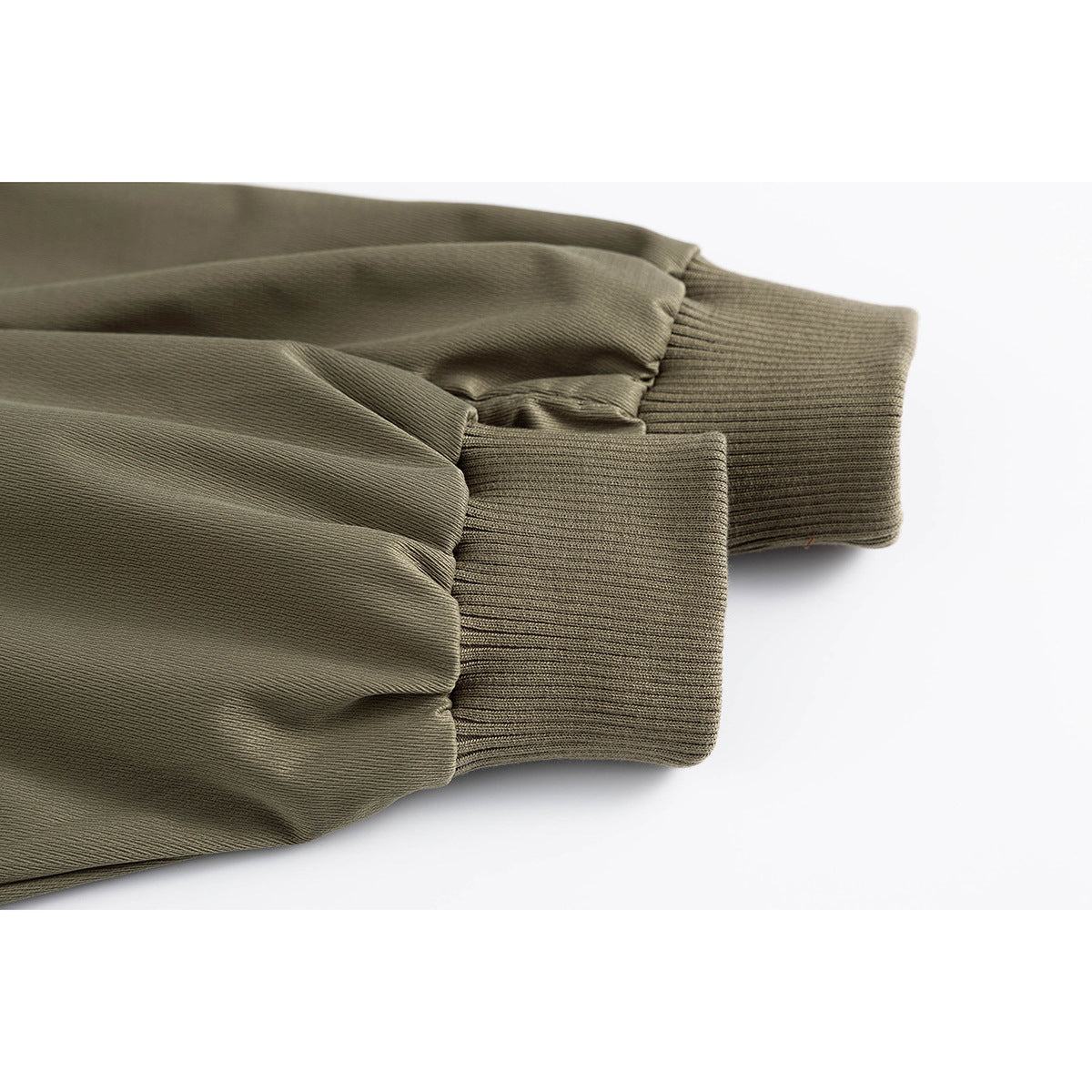 Close-up of an olive jacket sleeve gathered at a wide ribbed cuff.
