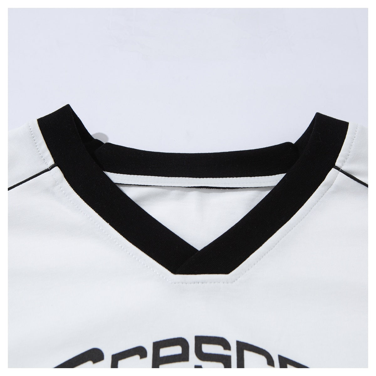 Close-up of the white T-shirt's black crew neckline and shoulder seams, with part of a black chest print visible below.