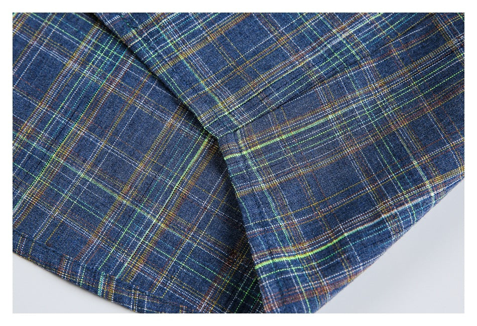 Close-up of dark blue plaid garment fabric with multicolored lines and a stitched seam.