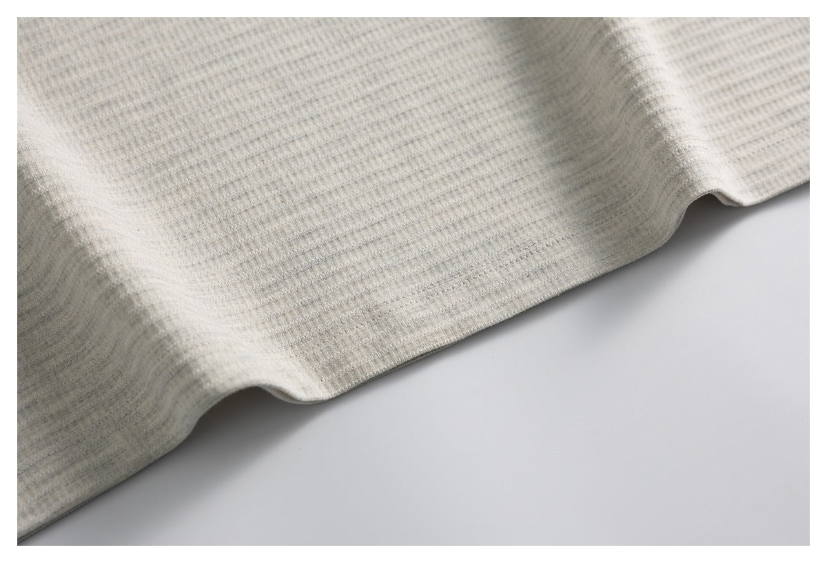 Close-up of the light heather-gray knit top's gently curved lower hem.