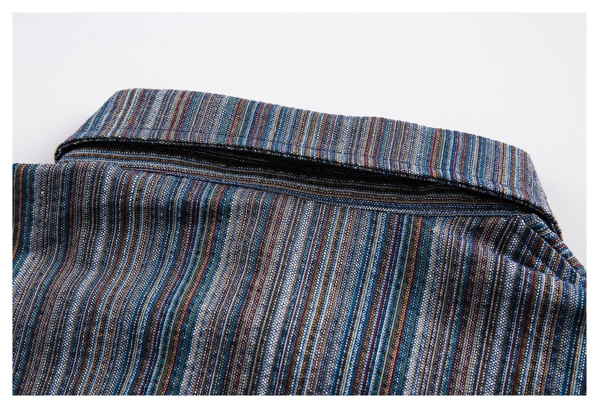 Close-up of a dark zipper opening on a garment with fine multicolored stripes.