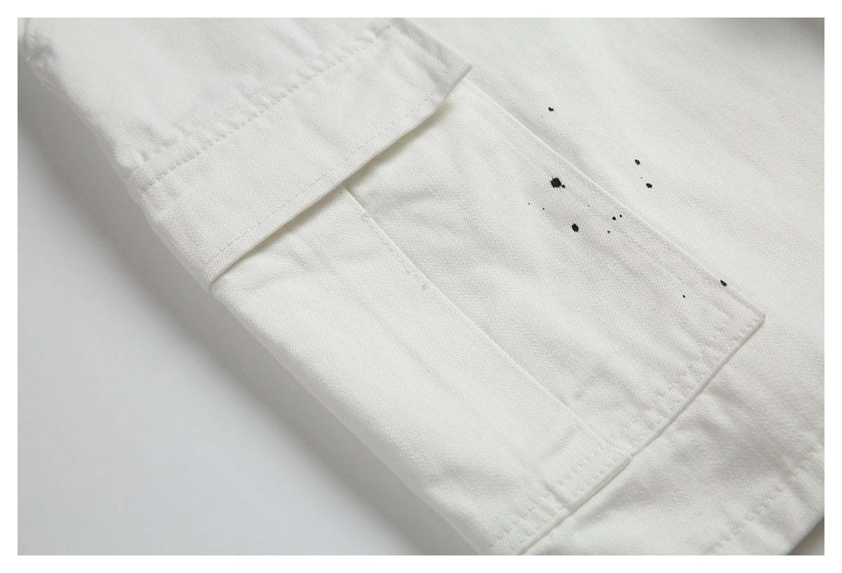 Close-up of an off-white pocket and seam with scattered black paint-like marks.