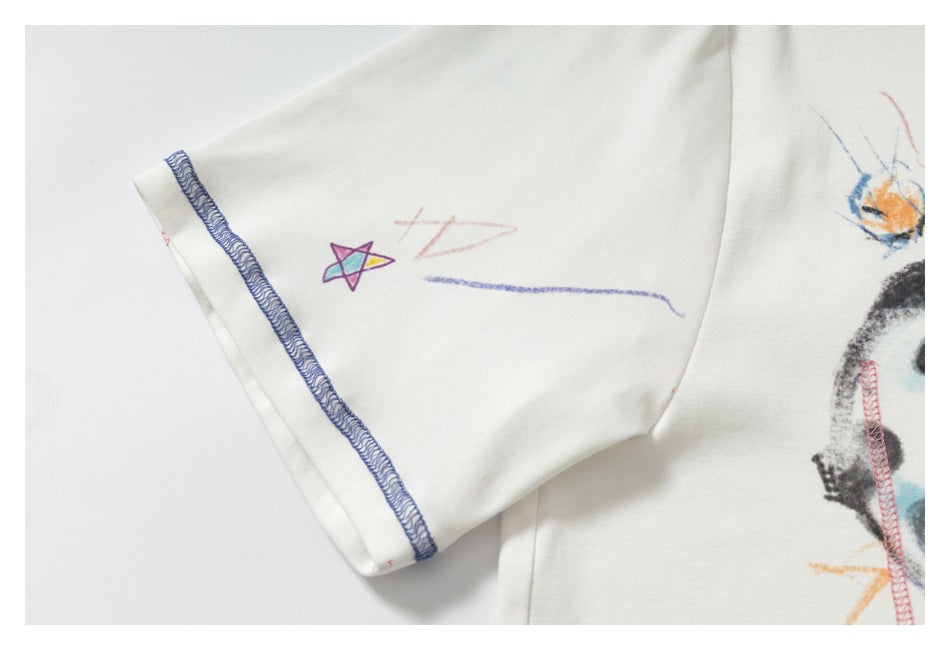 Close-up of a white shirt sleeve with a small colorful star doodle and blue overlock stitching at the cuff.