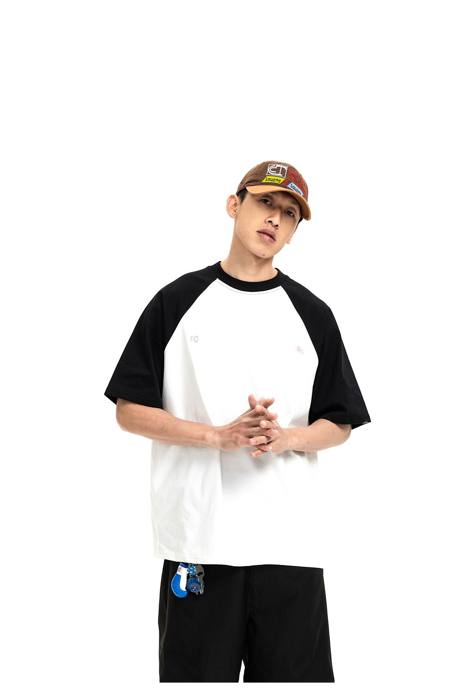 Model wearing a white raglan T-shirt with black sleeves and a small chest print, paired with black trousers.