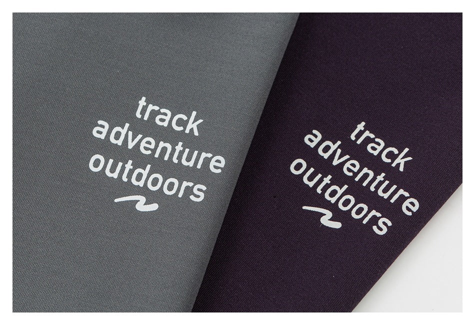 Close-up of white “track adventure outdoors” logos on gray and dark plum garment colorways.