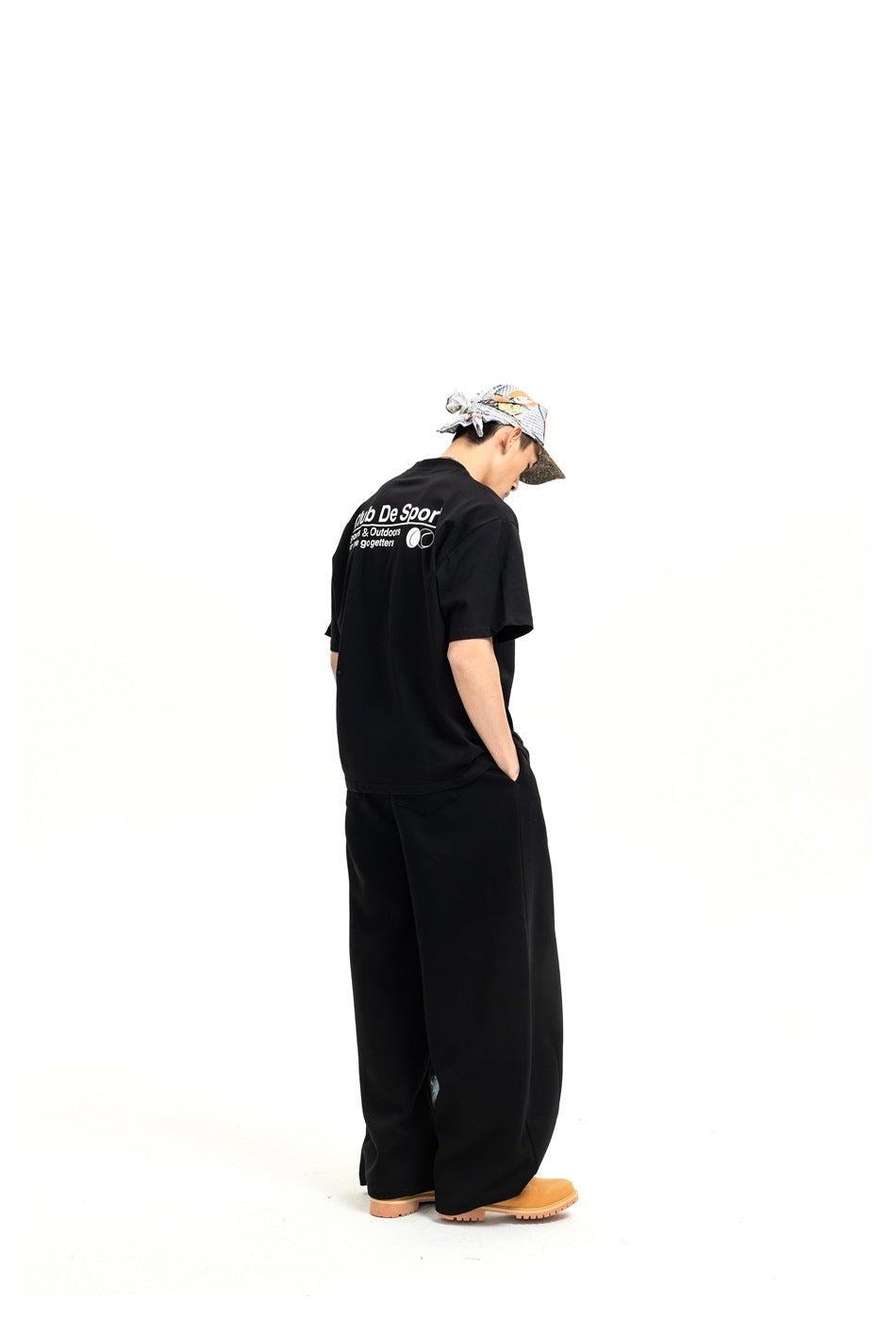 Rear view of a model in black wide-leg pants and a black T-shirt with white text across the back.
