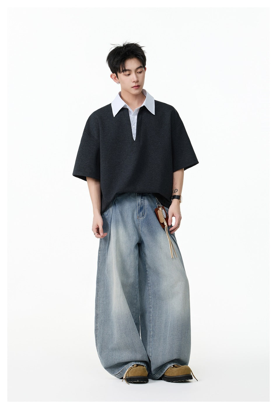 Model wearing an oversized charcoal short-sleeve top with a white pinstriped collar and placket, paired with wide-leg jeans.