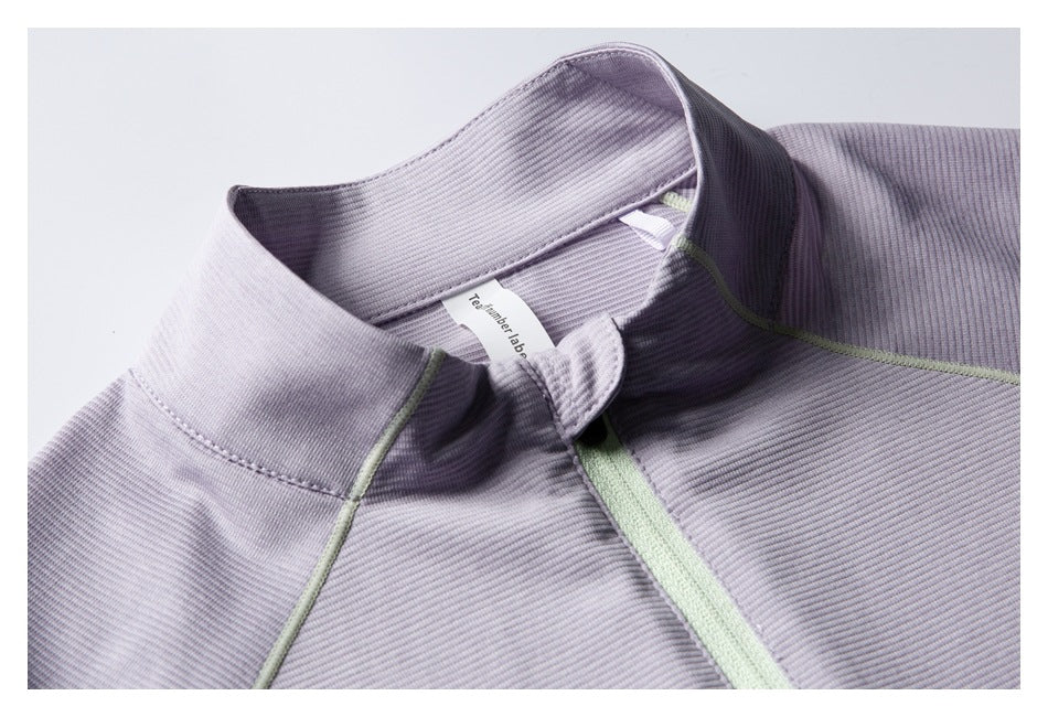 Close-up of the jacket’s ribbed collar, front zipper, pale green piping, and inner neck label.