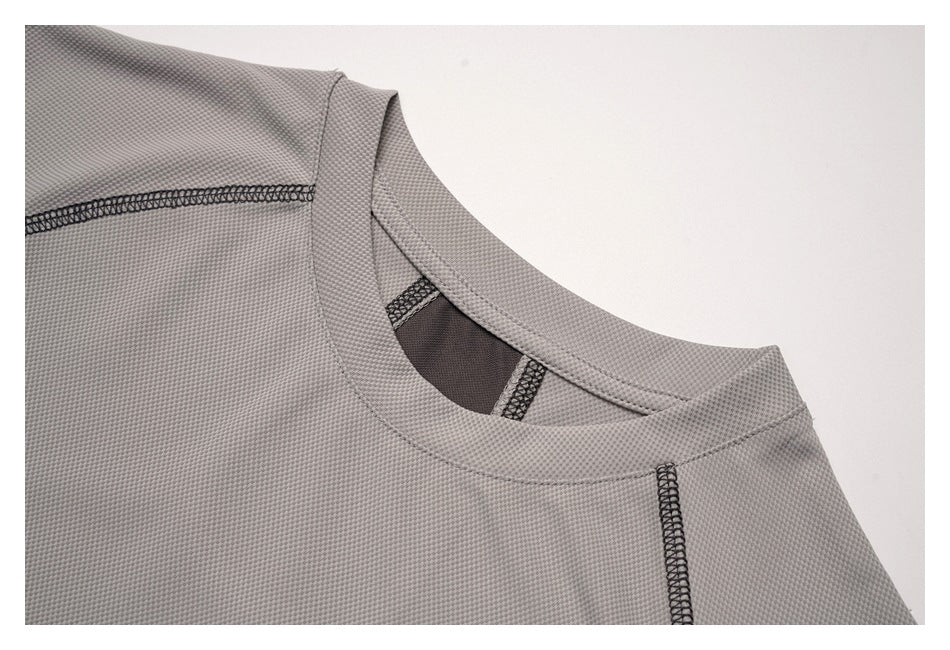 Close-up of the gray top's crew neckline, textured surface, and dark overlock stitching.