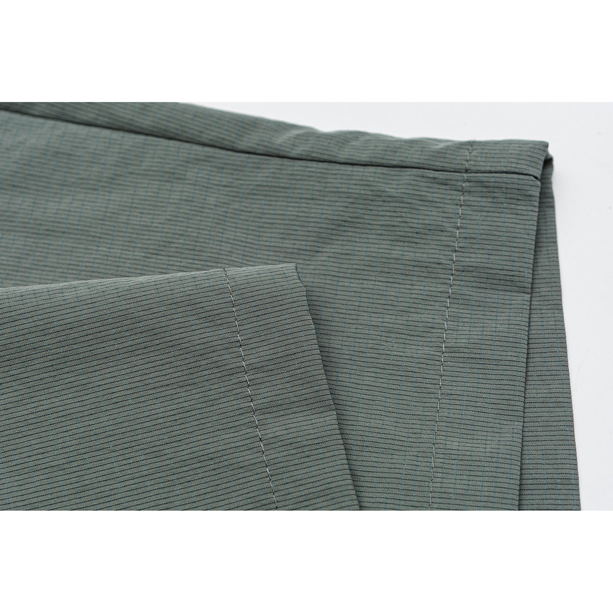 Close-up of gray-green striped shorts showing folded fabric panels and stitched seams.