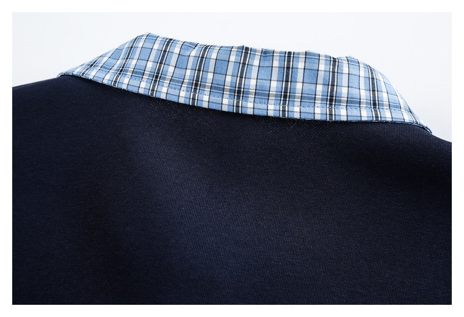 Close-up of a navy garment's back neckline with a blue, white, and black plaid collar.