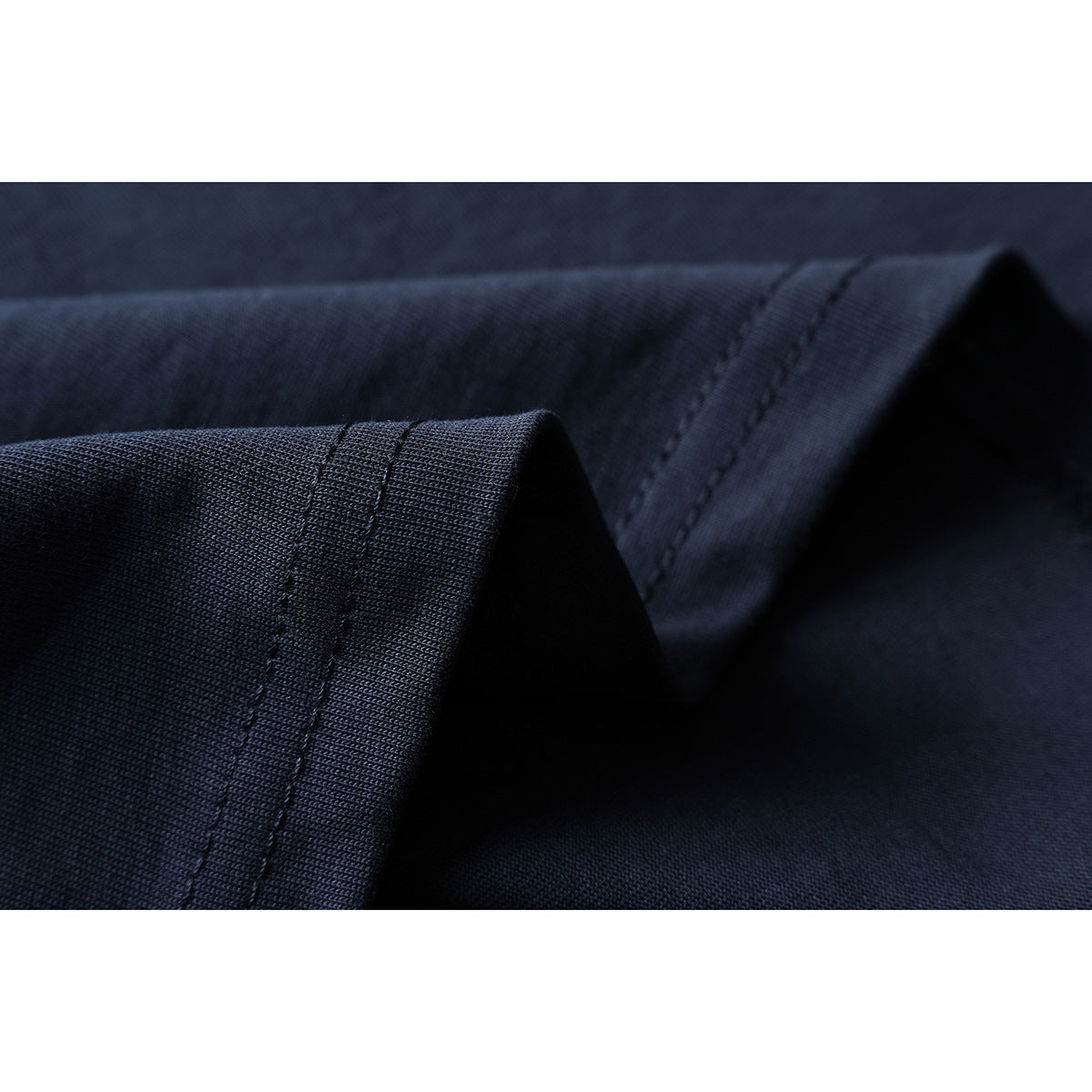 Macro view of dark navy fabric folded to show stitched seams and the knit texture.