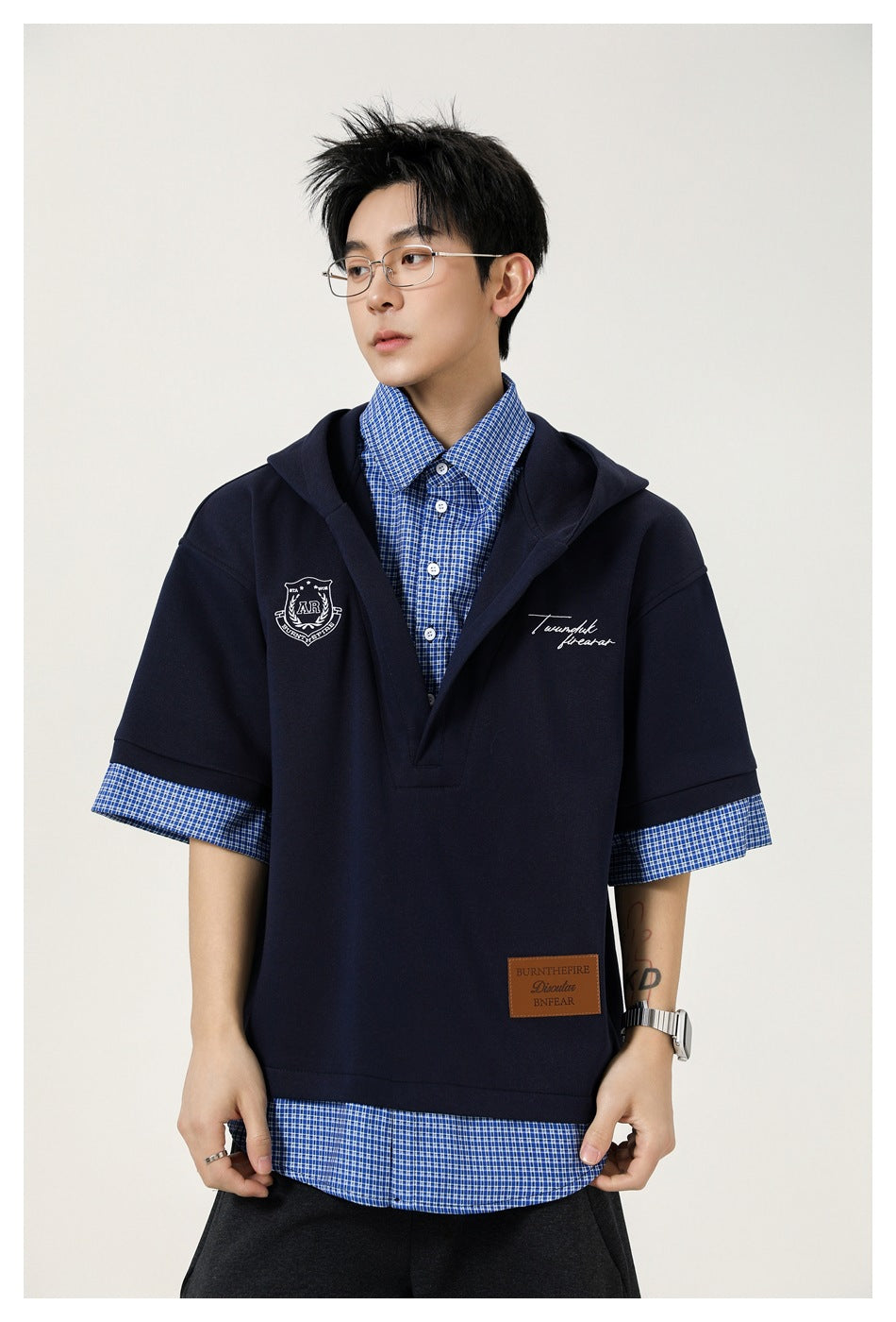 Model wearing navy hooded top with blue check collar, sleeve and hem layers, close three-quarter front view
