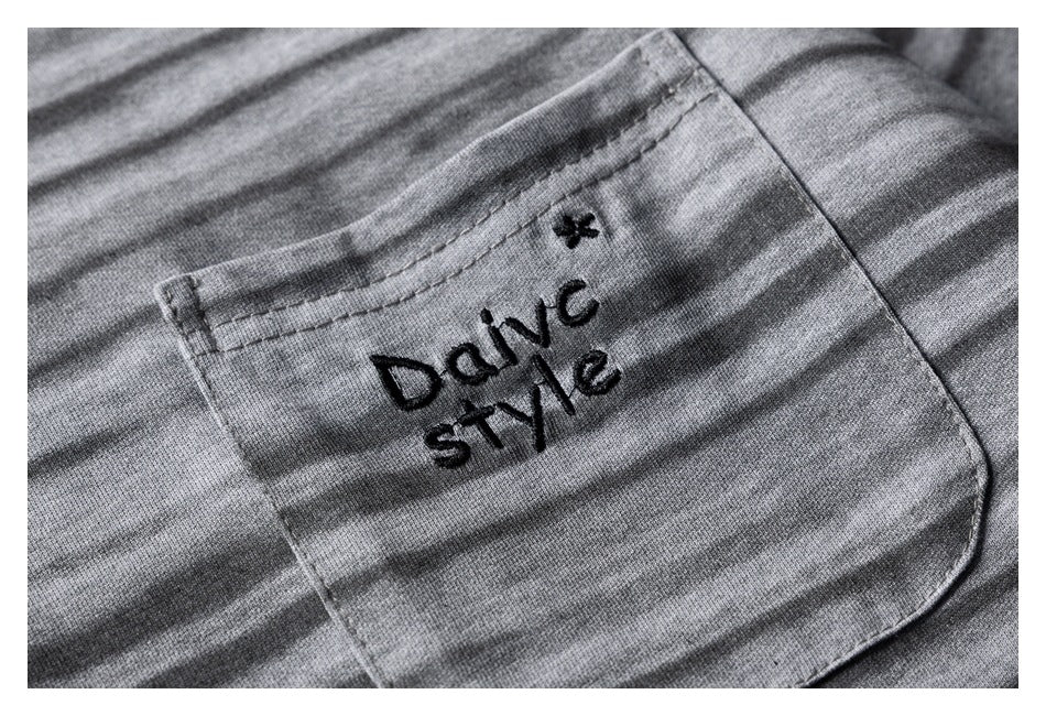 Close-up of a pocket on a gray striped garment, embroidered with the words “DaiVC style.”