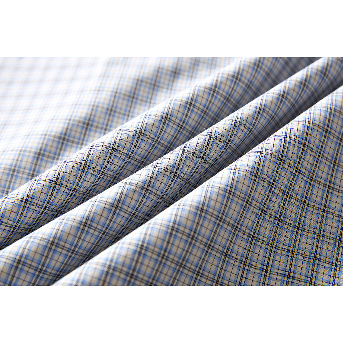 Close-up of light blue, gray, and tan plaid shirt fabric draped in soft folds.