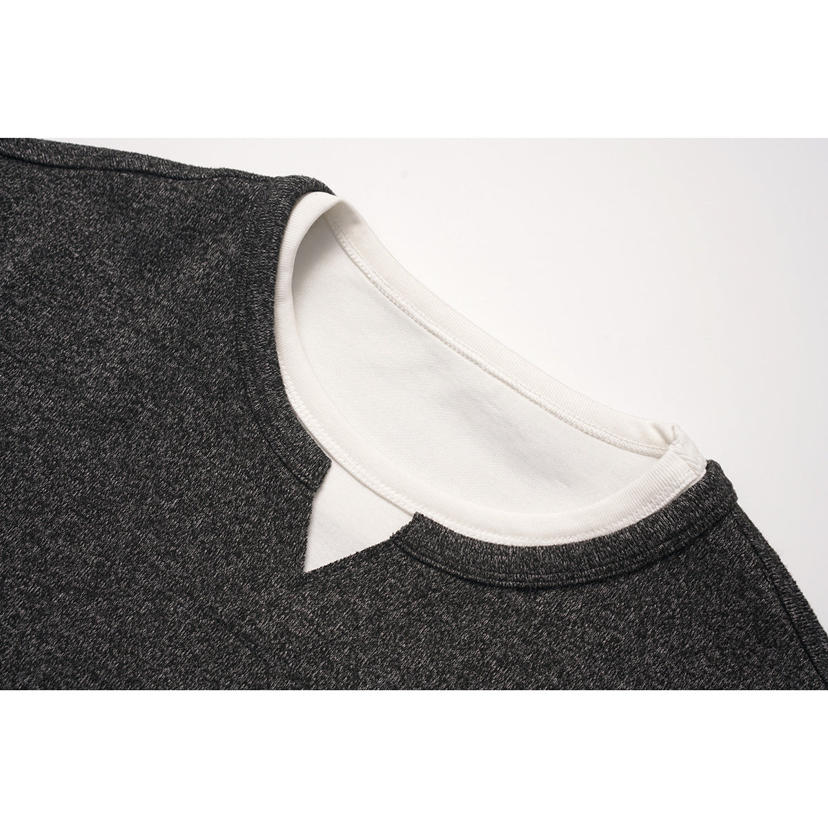 Close-up of a charcoal marled crew neck with a white inner layer showing at the neckline.