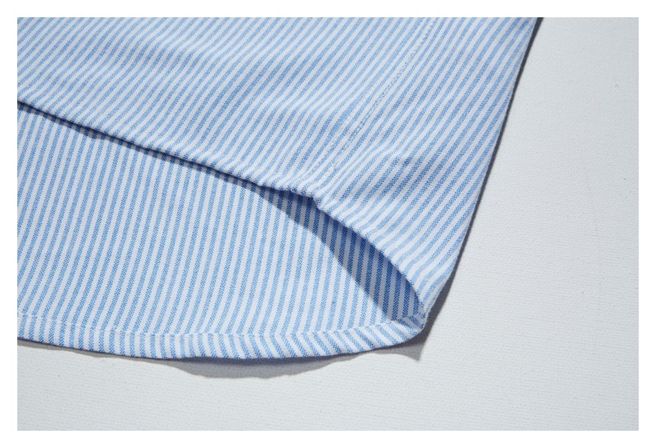 Close-up of the curved bottom hem of a blue-and-white striped shirt.