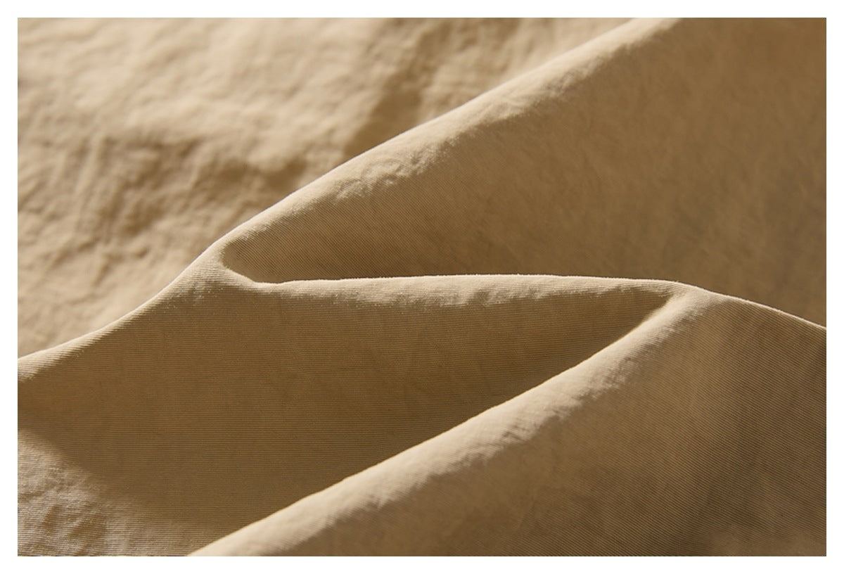 Macro view of the beige trouser fabric, showing its fine ridged texture and soft folds.