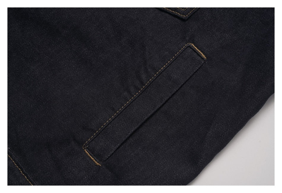 Close-up of a narrow stitched tab on dark denim fabric.