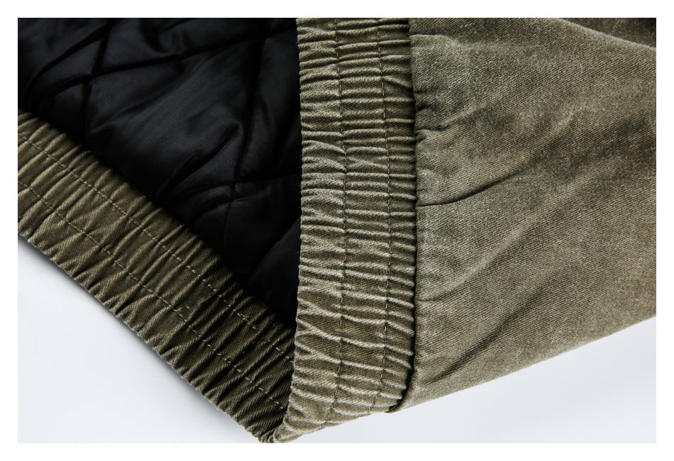 Close-up of an olive-gray garment opening, showing black quilted lining and a gathered edge.