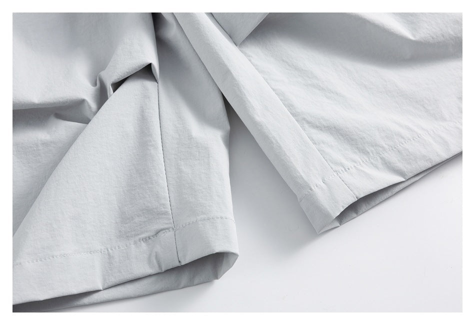 Close-up of the stitched hems and leg openings of light gray shorts.