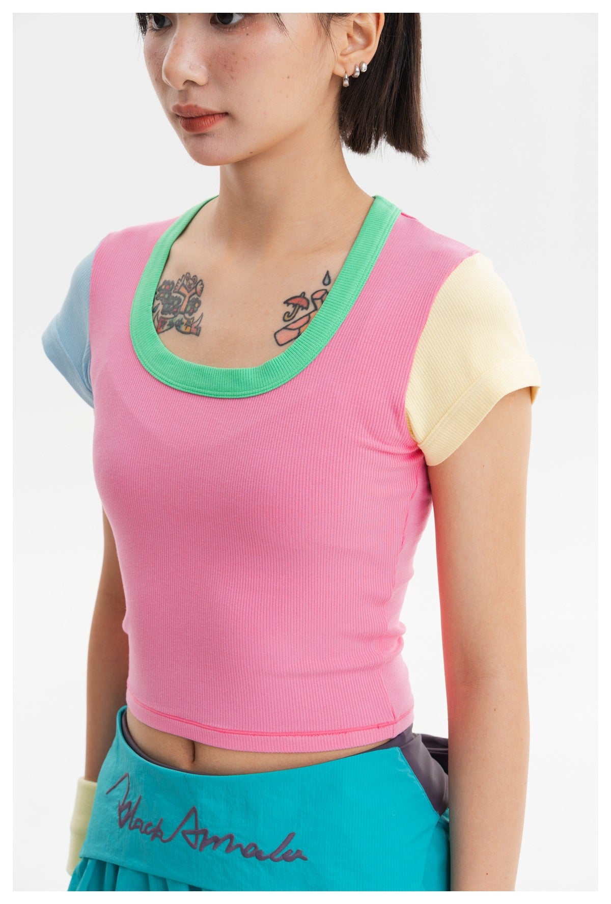 Close view of a pink ribbed crop top with a green neckline and pale blue and yellow sleeves.