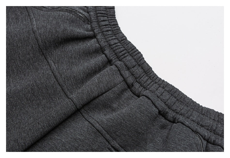 Close-up of charcoal gray jogger pants showing the elastic waistband and curved pocket seam.