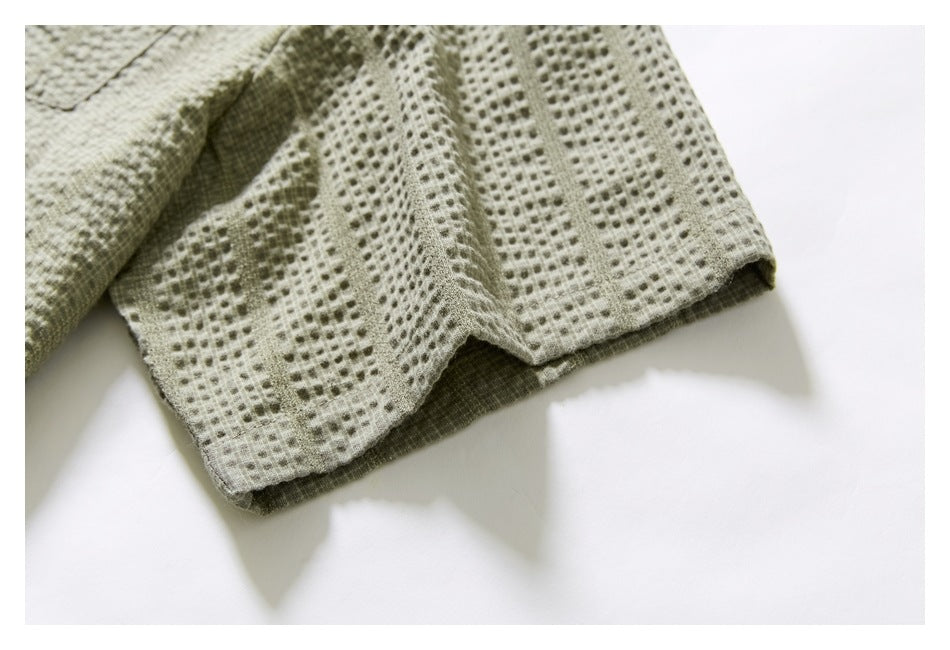 Close-up of the light olive shirt's textured sleeve and stitched cuff edge.