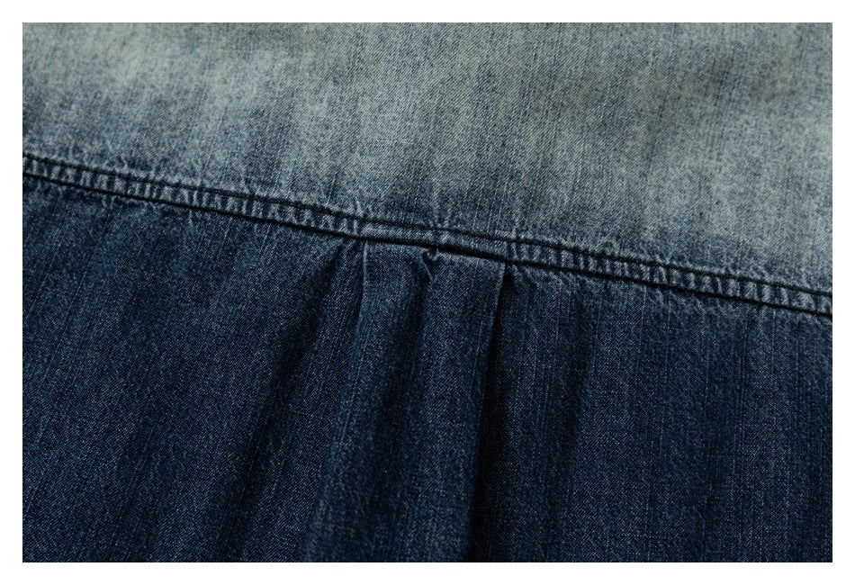 Close-up of a stitched seam and pleat in faded blue denim.