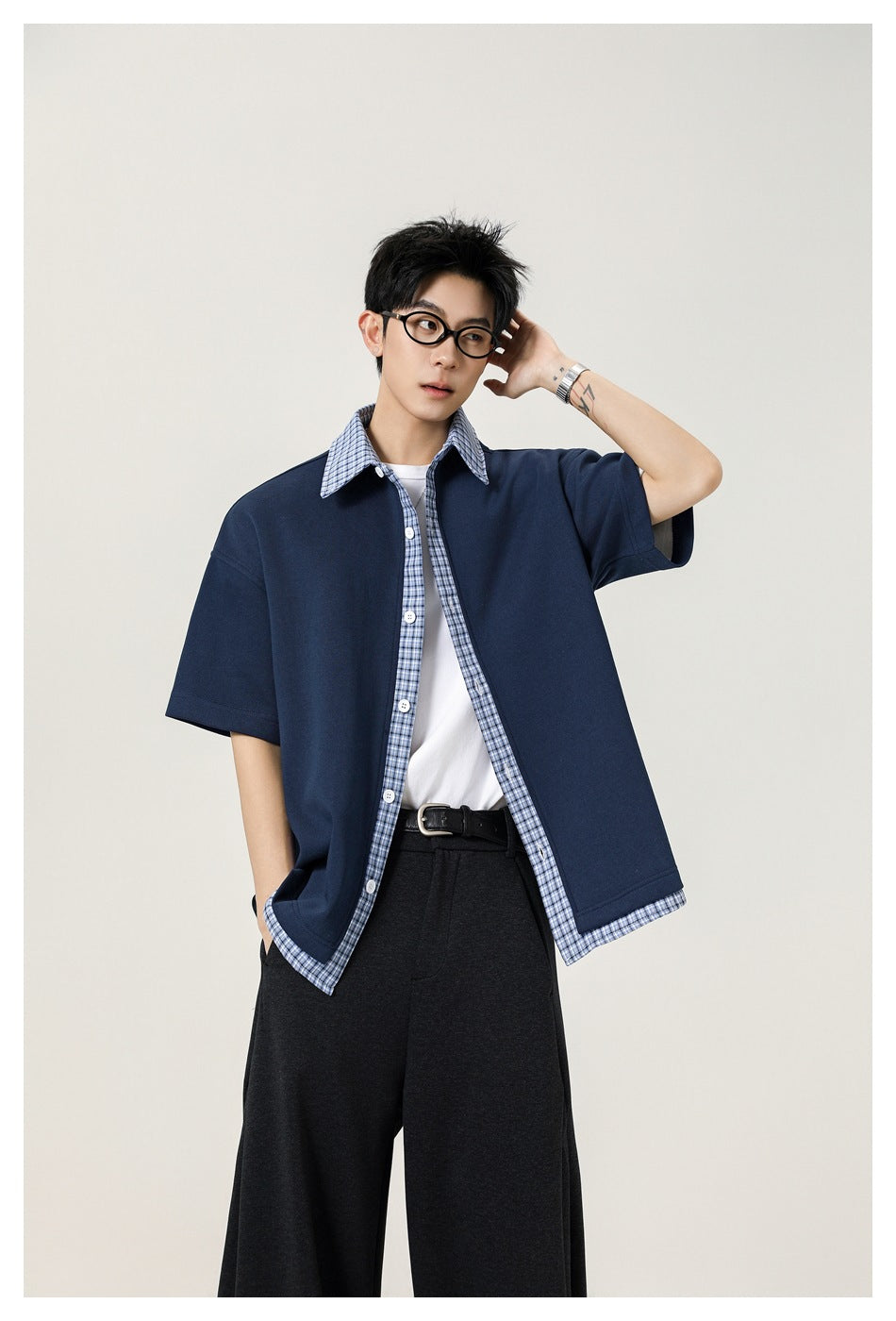 Model wearing an oversized navy short-sleeve shirt with blue plaid collar, button placket and hem trim.