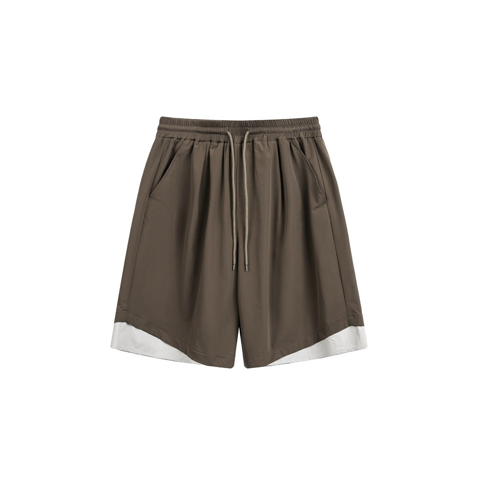 Brown knee-length drawstring shorts with side pockets and off-white curved hem panels, front view