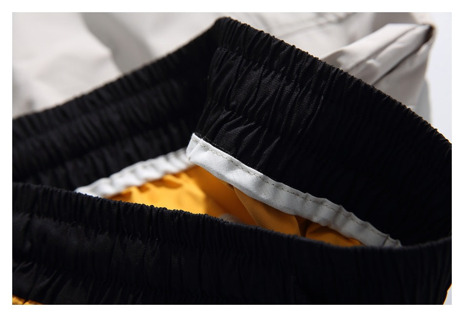 Close-up of the black gathered elastic waistband interior, with white stitching and mustard-yellow fabric beneath.