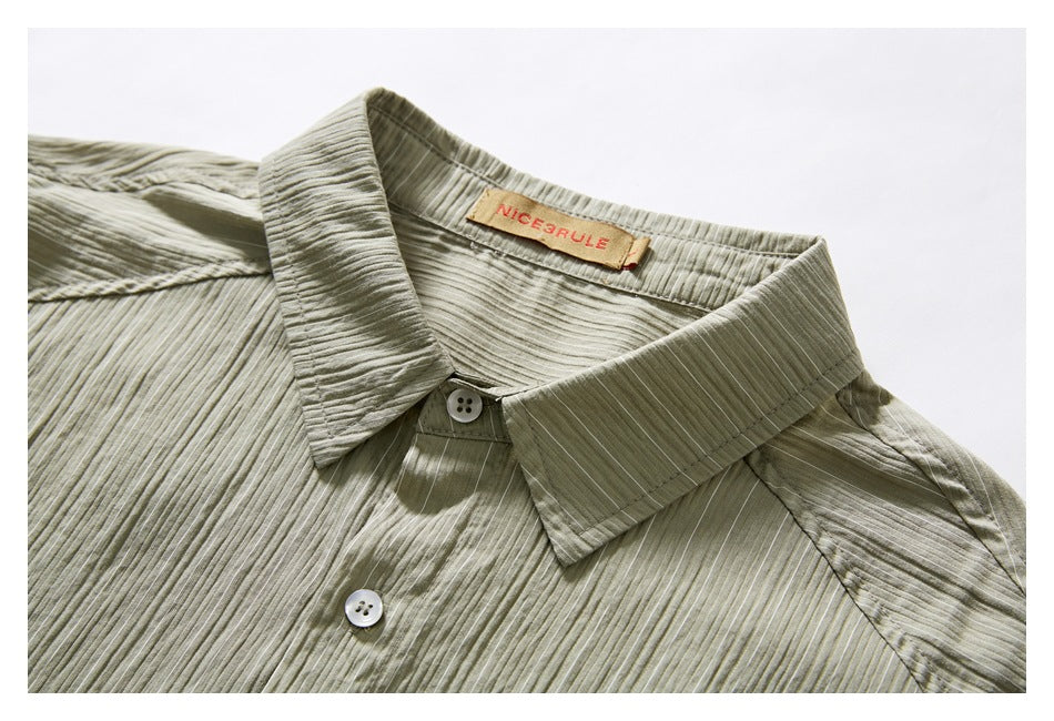 Close-up of an olive-gray shirt collar and buttons, showing its textured vertical stripes.