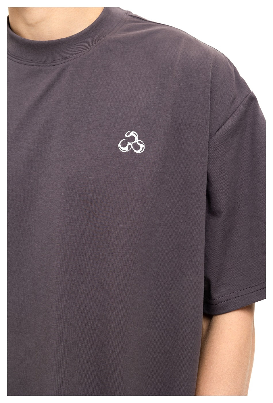 Close-up of a person wearing a charcoal-gray short-sleeve T-shirt with a small white chest emblem.