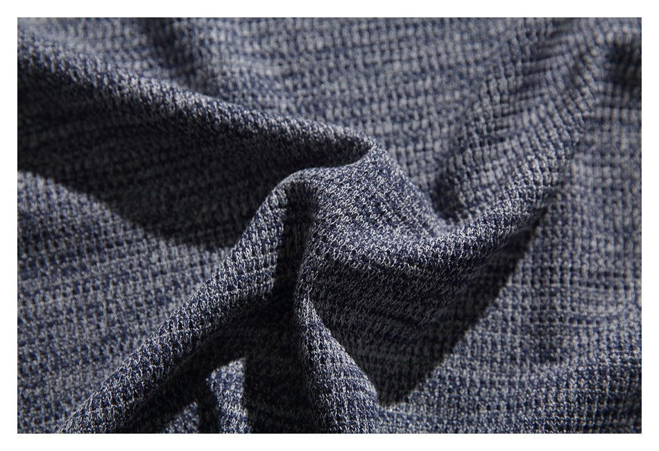 Close-up of dark blue-gray knit fabric gathered into folds, showing its textured stitch pattern.