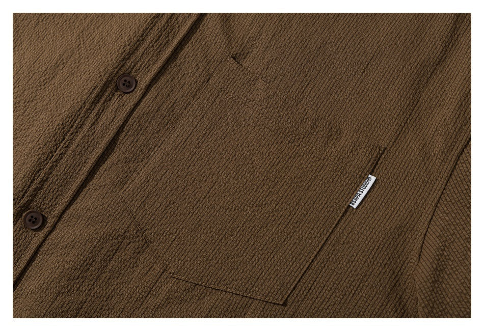 Close-up of the brown shirt's button placket, chest pocket, and small sewn label.