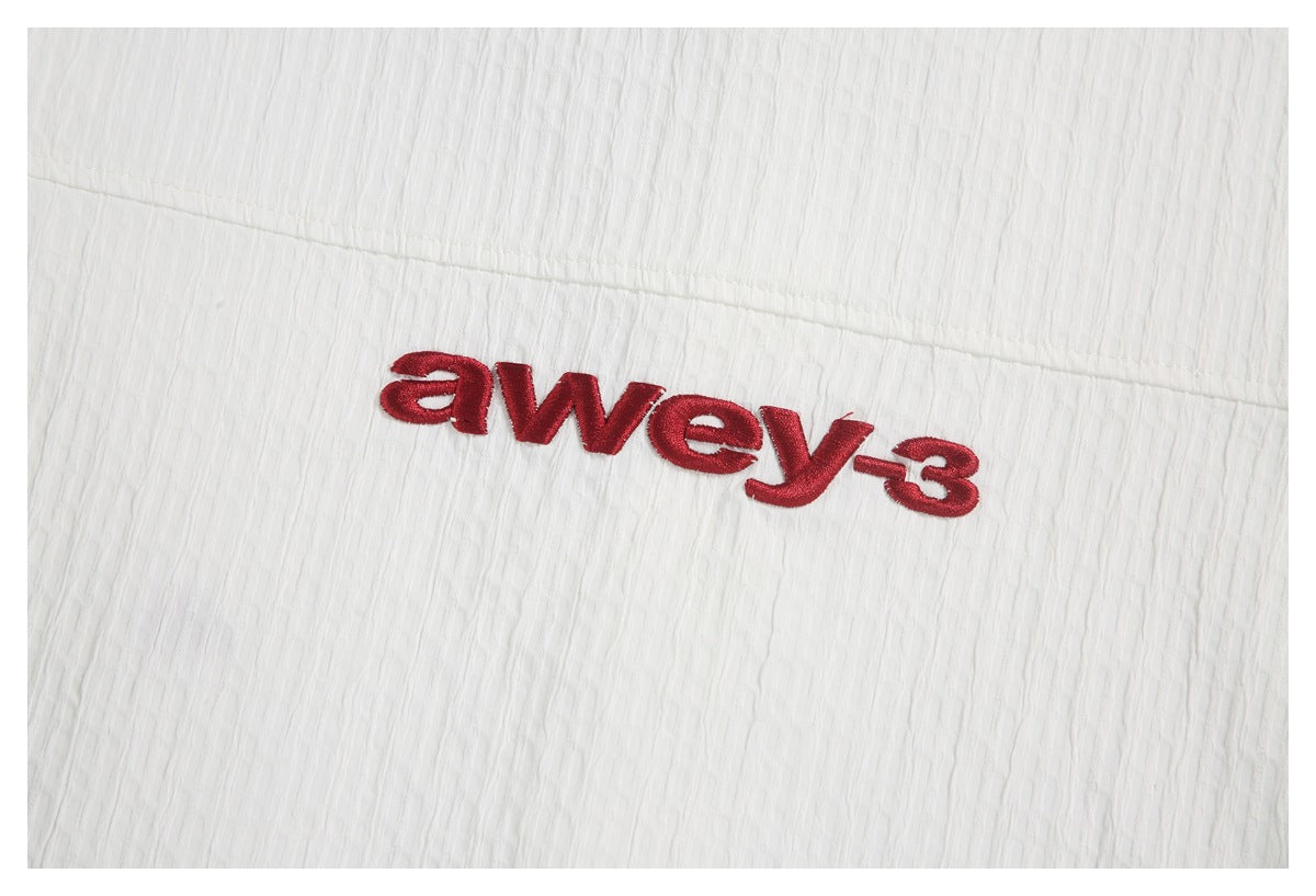 Red embroidered lettering on the white textured shirt fabric.