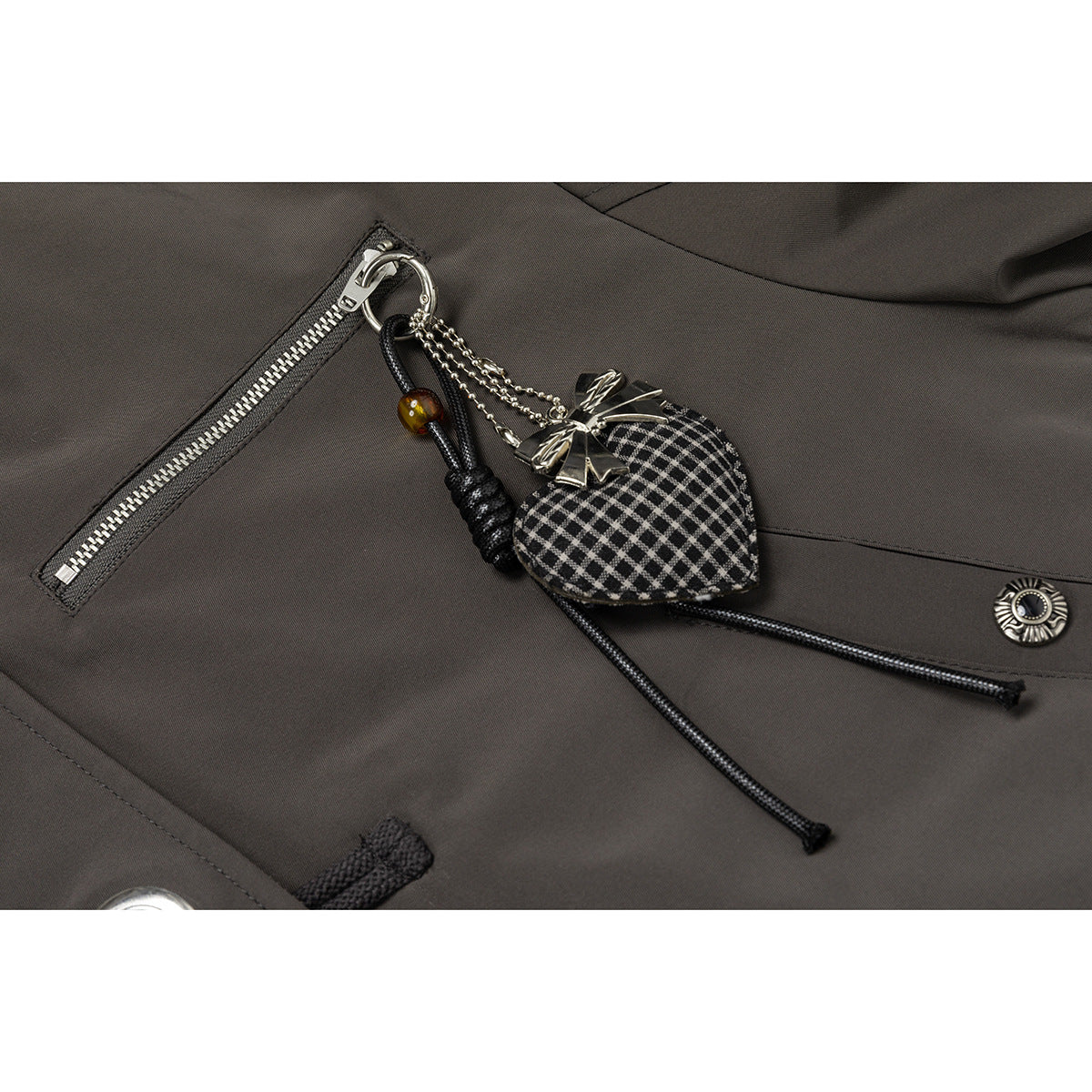 Close-up of the jacket's silver zip pocket and dangling black-and-white patterned charm.