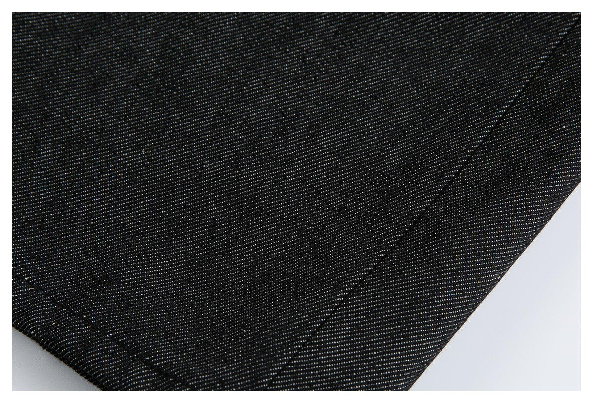 Extreme close-up of black denim-like fabric with a diagonal stitched seam.