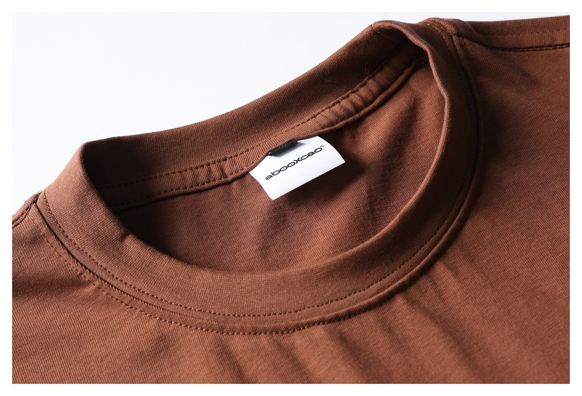 Close-up of a rust-brown T-shirt neckline, collar stitching, and a white inner brand label.