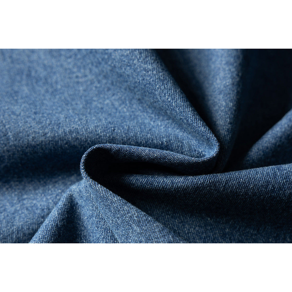 Macro view of blue denim fabric gathered into soft folds.