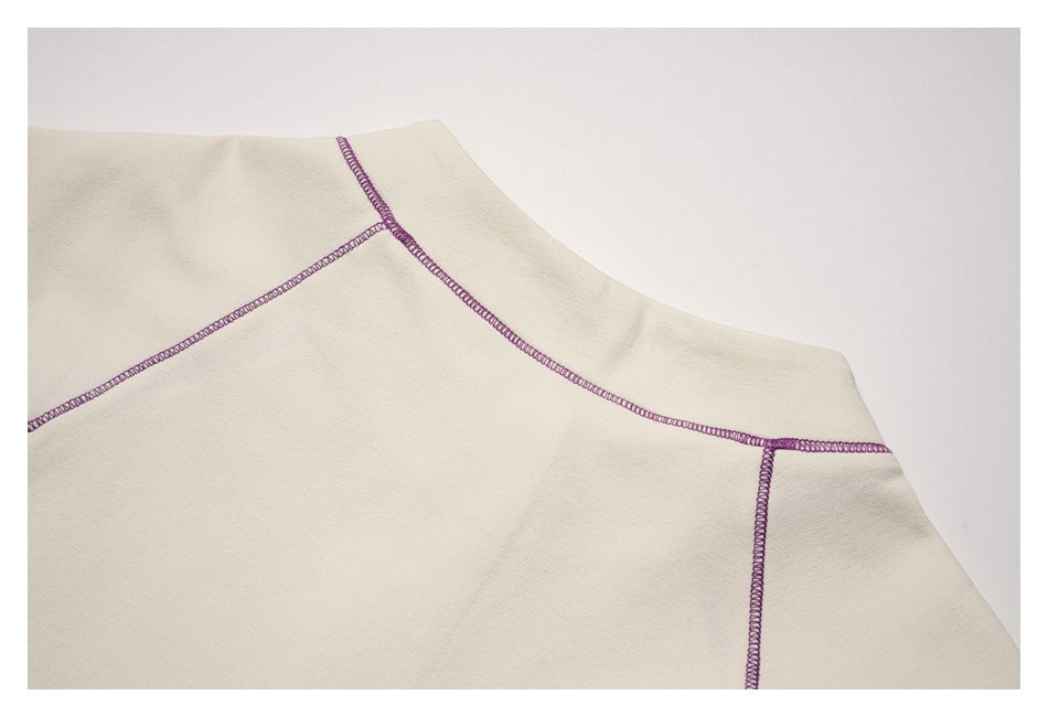 Close-up of an ivory garment neckline area with purple overlock seams.