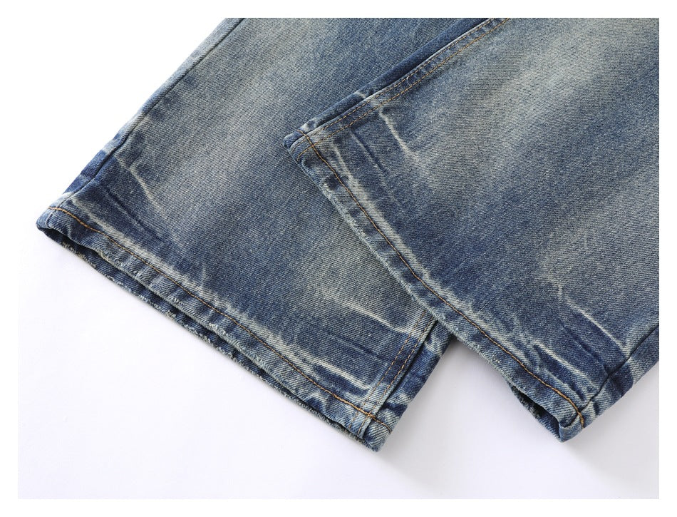 Close-up of blue faded denim trouser hems with double rows of tan stitching.
