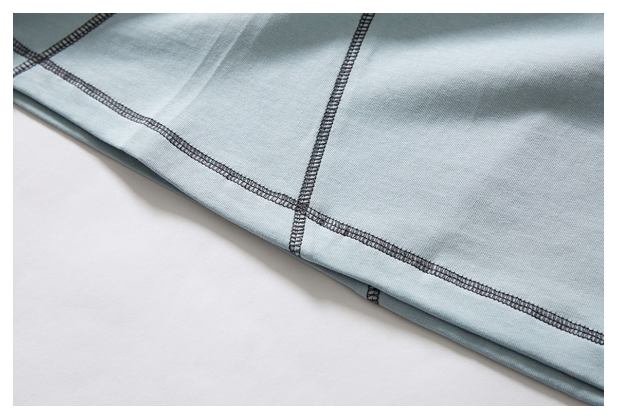 Close-up of a pale blue garment hem and intersecting dark overlock seams.